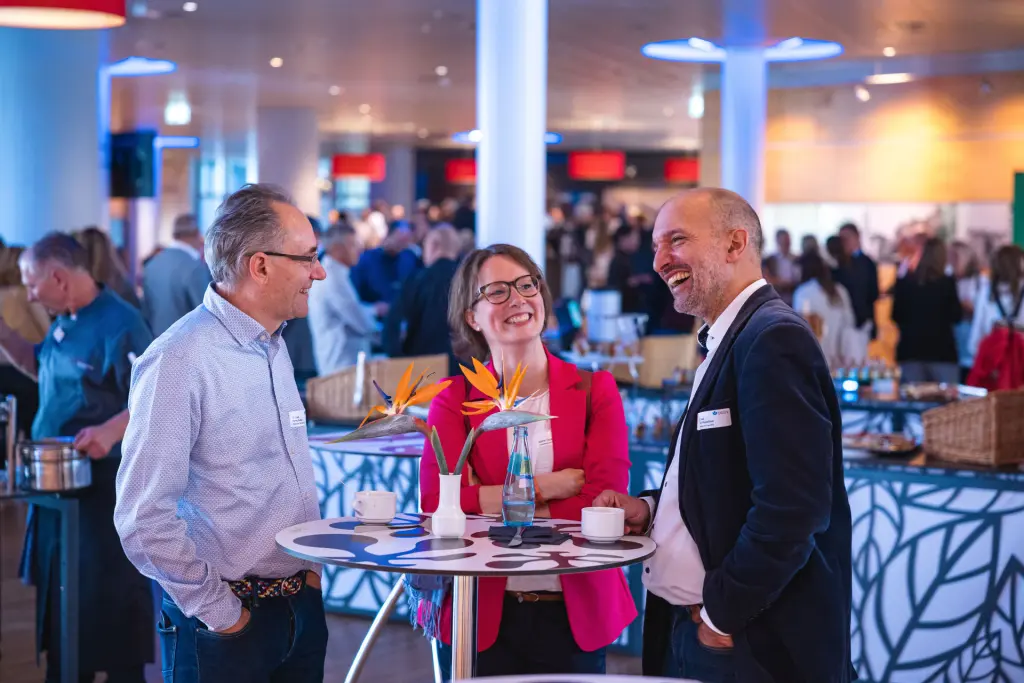 Professionelle Eventfotografie bei einem Business-Event: Drei Personen im Gespräch während eines Networking-Events, aufgenommen von KreativMedia.
