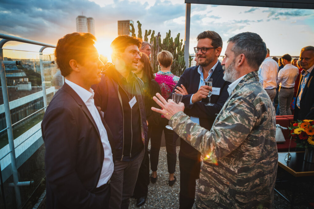 Geschäftliches Networking auf einer Dachterrasse in Hamburg bei Sonnenuntergang, aufgenommen von einem Eventfotografen.